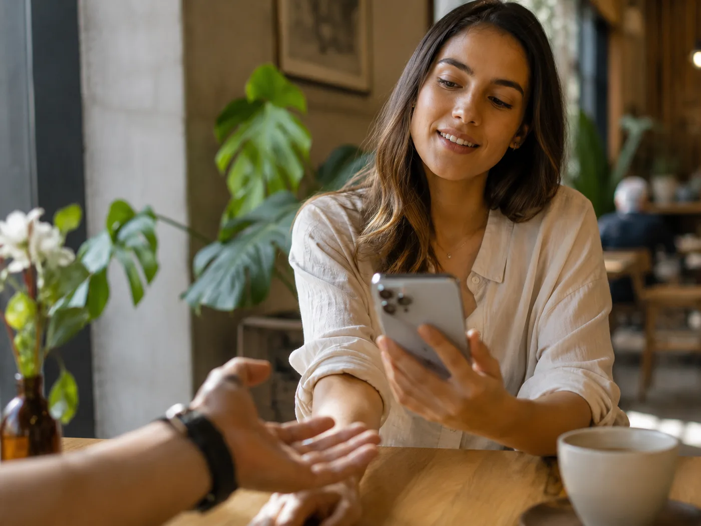 Mujer mostrando su celular a otra persona en una cafetería
